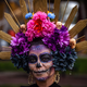 A woman wears a crown of colorful flowers and skulls.